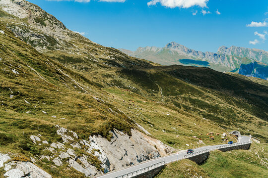 Winding road cuts through green mountain slopes in Italian Alps