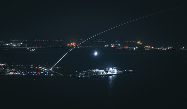 Aerial view of Santos Dumont Airport at night with illuminated runways and a light trail from an aircraft taking off over the dark waters in Rio de Janeiro, Rio de Janeiro, Brazil.