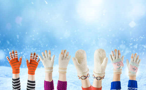 Holiday Christmas children hands raised up with diverse winter gloves mitten