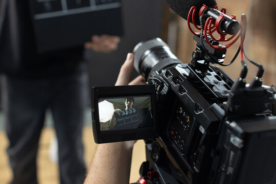 Cinema camera rig is recording scene on film set with flip-out monitor showing clapperboard