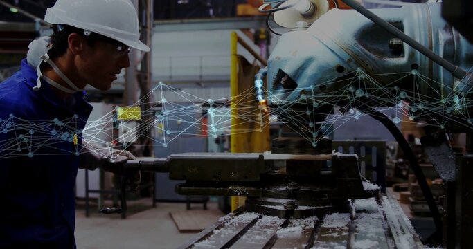 Operating machinist in hard hat, coveralls checking mill vise with network overlay, shop