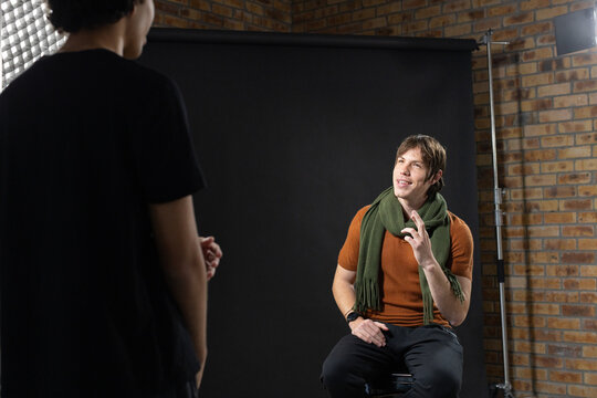Diverse male collaborators posing in studio on stool with black backdrop, softbox, scarf