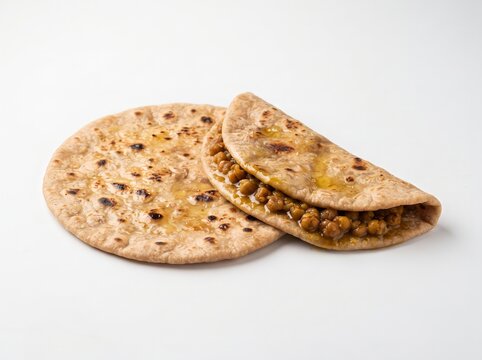 Two puran poli flatbreads, one folded to show chana dal filling
