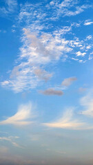A bright blue vertical sky view in October, filled with diverse cloud patterns ranging from wispy cirrus at the bottom to patchy altocumulus higher u © cilicia