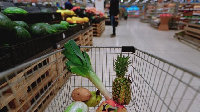 Timelapse of shopping cart moving through a supermarket as a customer selects fresh vegetables. Various products are added to Grocery trolley at supermarket. Healthy food, variety of vegetables