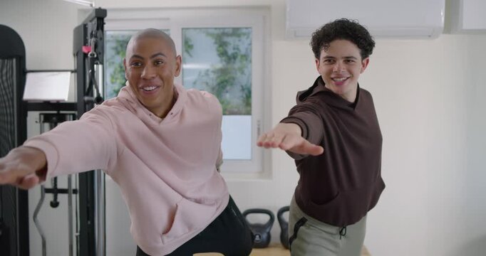 Diverse male friends following leader cue, doing synced arm-extensions in home gym with weights
