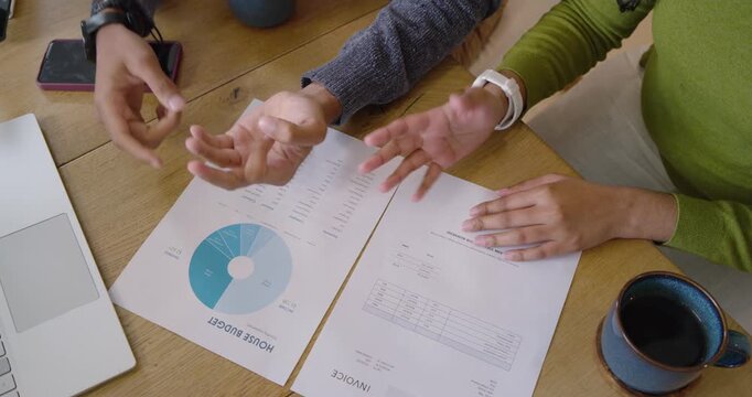 Indian colleagues reviewing HOUSE BUDGET and INVOICE at table pointing, comparing