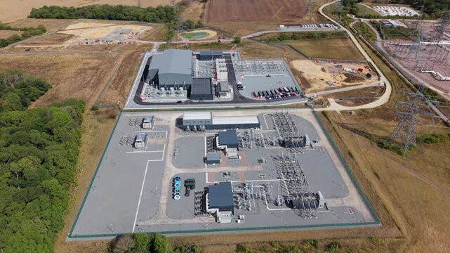 Aerial view of a massive 400 kV electrical substation with transformers, switchgear, and transmission pylons in Bramford, Suffolk, England, UK