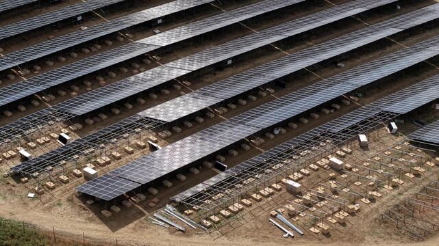 Close up aerial view of photovoltaic solar panels and metal mounting frames under construction on a rural site in England, UK