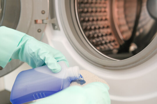 Washing machine cleaning, pouring liquid appliance cleaner onto a cloth for household cleaning and routine maintenance