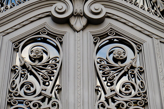 Ornate gray carved double door with scrollwork and arched top