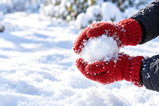 Mittened Hands Packing Fresh Snow Into Snowball On Sunny Day