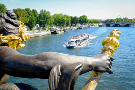 Gilded bridge sculpture overlooking Seine with tour boat