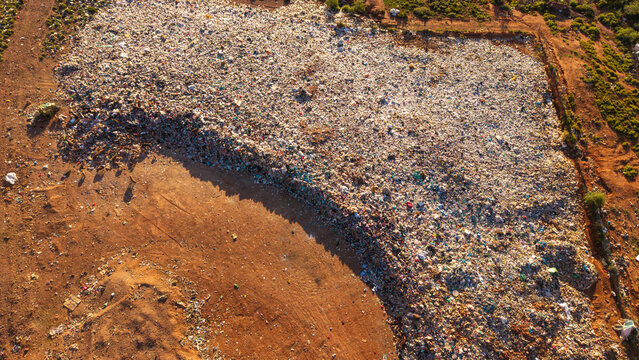 Aerial view of an informal pig farm at a landfill site with animals feeding from discarded waste, highlighting rural survival practices in Ladismith, Western Cape, South Africa.