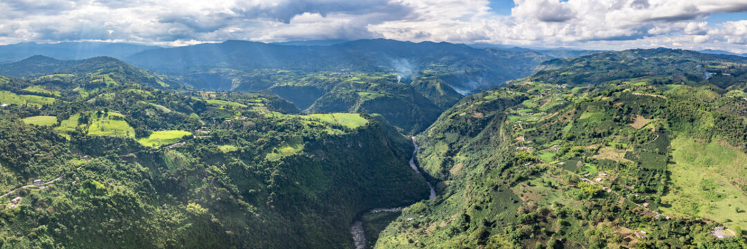 Aerial view of La Chaquira canyon with the Magdalena River winding through lush green mountains and agricultural fields in San Agustin, Huila, Colombia.