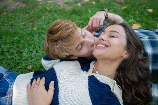 Happy young couple sharing a tender kiss on grass