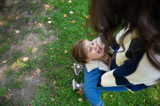 Mother holding laughing child playing outdoors with joy
