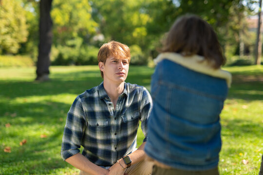 Young man talking to woman in park outdoors