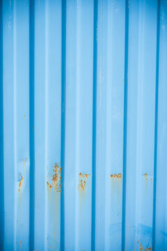 Weathered blue corrugated metal wall with rust stains and industrial texture