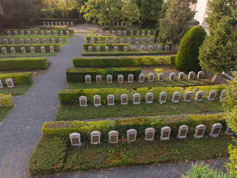 Aerial view of Eppegem Military Cemetery with rows of World War I war graves marked by headstones set within manicured green hedges and gravel paths in Zemst, Flanders, Belgium.