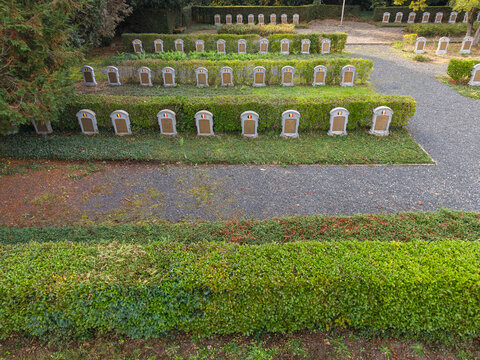 Aerial view of Eppegem military cemetery with rows of white headstones set among manicured green hedges and gravel paths in Zemst, Flanders, Belgium.