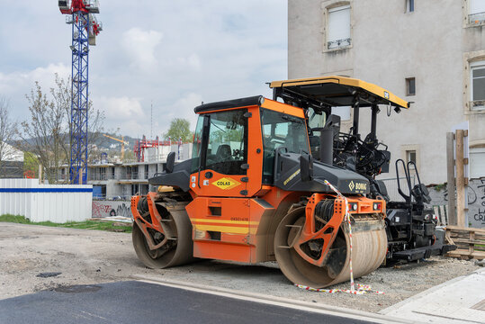Nancy, France - April 13th 2019 : View on an orange tandem roller Bomag BW 174 AP for compacting asphalt on a road during road works alongside another roller.