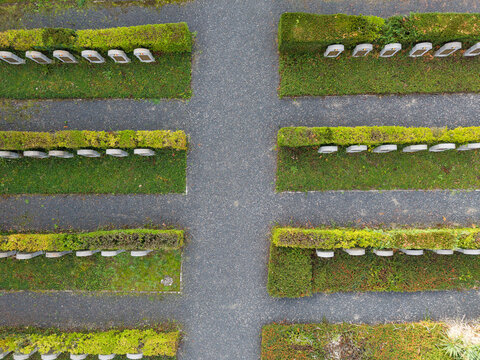 Aerial view of Eppegem military cemetery with rows of white war graves separated by manicured green hedges and gravel paths in Zemst, Flanders, Belgium.