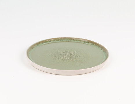 Sage green empty ceramic plate with speckled glaze on white background, perspective tableware mockup
