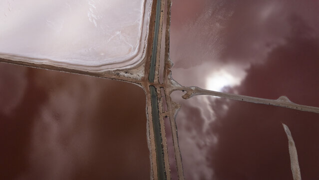Aerial view of Hutt Lagoon with its vibrant pink waters, salt crusts, and intersecting dirt roads in Yallabatharra, Western Australia, Australia.