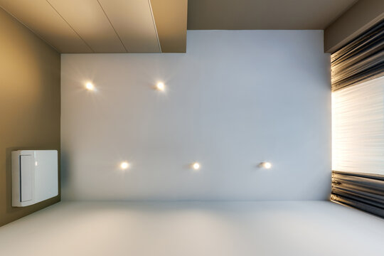 suspended ceiling with halogen spots lamps and drywall construction in empty room in apartment or house. Stretch ceiling white and complex shape.