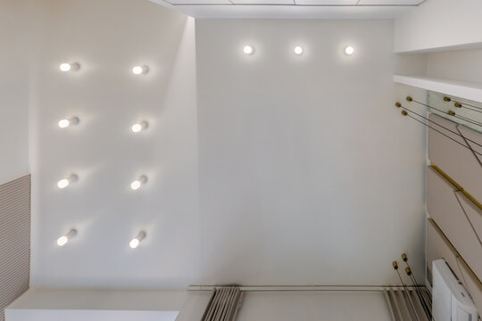 suspended ceiling with halogen spots lamps and drywall construction in empty room in apartment or house. Stretch ceiling white and complex shape.