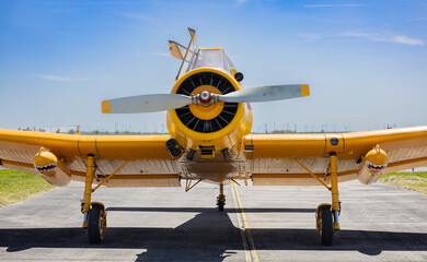 Front View of Yellow Agricultural Crop Duster Airplane Parked on Runway Under Blue Sky © Diatlova Tetiana