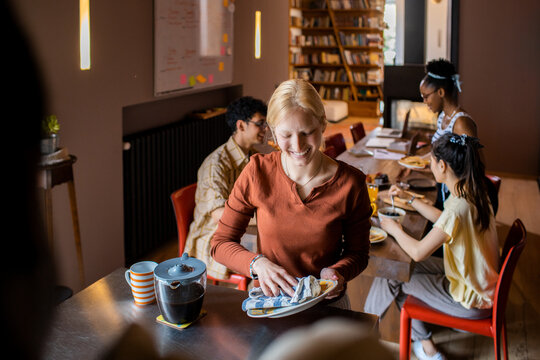 Smiling woman drying plates in shared kitchen