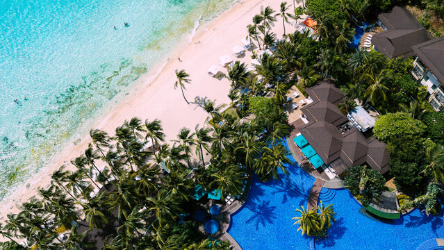 Malay, Philippines - 01 October 2026: Aerial view of Boracay Island showing a pristine white sand beach, clear turquoise water, dense palm trees, and a large resort swimming pool.