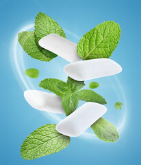 Menthol chewing gum pieces and mint leaves in air against blue background © New Africa