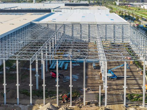 Genk, Belgium - 12 October 2026: Aerial view of the industrial construction site at Genk-Zuid, featuring a steel roof structure, concrete columns, and machinery during warehouse expansion.