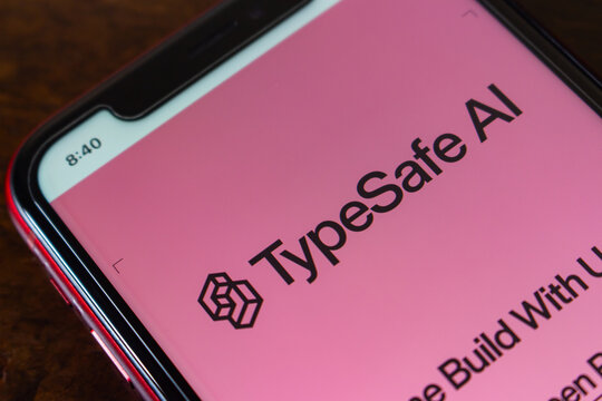 Quetzaltenango, GUATEMALA - Oct 2 2026 : iPhone showing the TypeSafe AI wordmark and isometric cube logo in black on a pink web page, with partially visible text below.