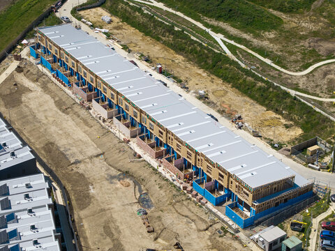 Melbourne, Australia - 08 October 2026: Aerial view of a residential construction site featuring a long row of townhouses under development with wooden framing and metal roofing.