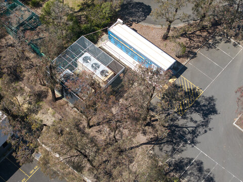 Melbourne, Australia - 08 October 2026: Aerial view of data centre and HVAC units surrounded by trees and a parking lot.