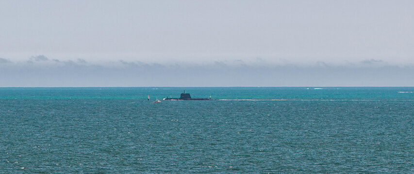 Fremantle, Western Australia, Australia - 06 October 2022: Aerial view of a submarine navigating the waters near Fremantle Harbour with a small escort boat nearby.