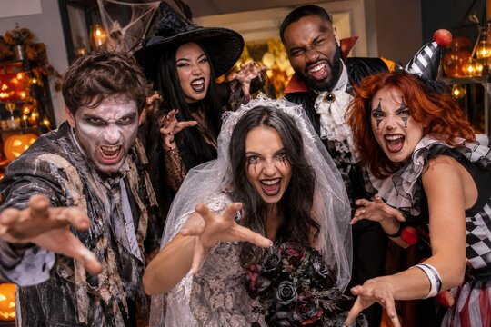 Friends in spooky Halloween costumes making playful scary faces at a party