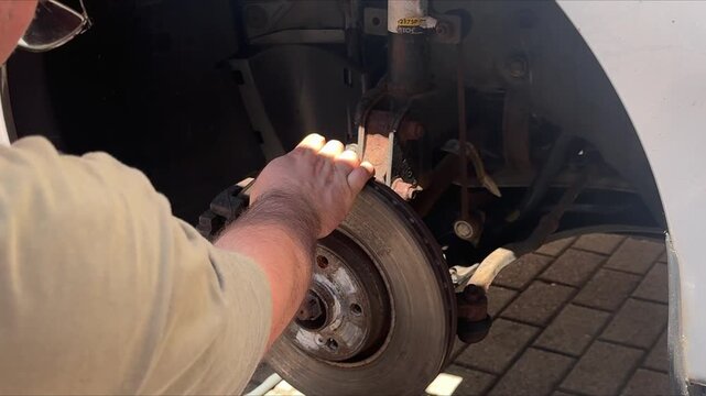 Mechanic replacing a suspension strut with hand tools. Automotive repair, DIY vehicle maintenance, shock absorber replacement, brake service and professional garage work.