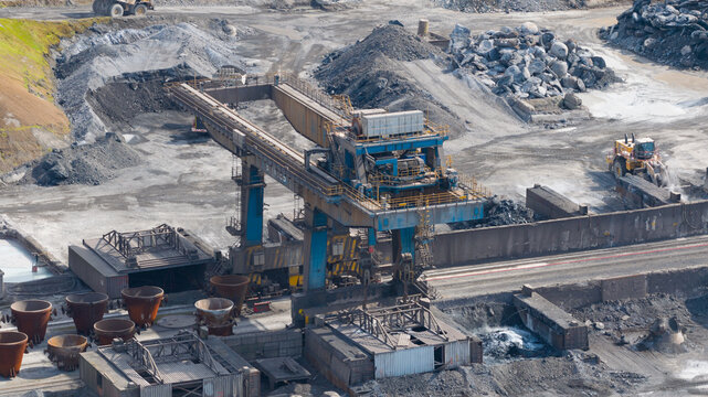 Velsen-Noord, Netherlands - 05 May 2026: Aerial view of Tata Steel industrial site featuring a large gantry crane, slag pots, and piles of raw materials in a sprawling manufacturing facility.