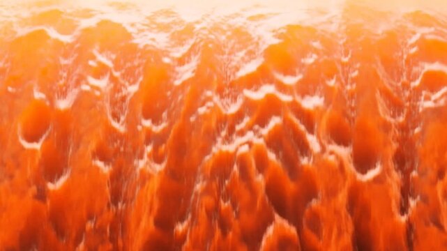 Orange ocean waves roll and break into white foam across the sea
