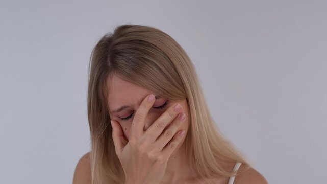 Young blonde woman making a facepalm gesture, expressing disappointment, frustration, embarrassment and emotional exhaustion