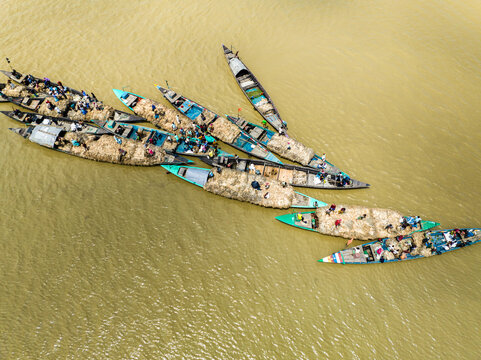 Kazipur, Bangladesh - 24 August 2024: Aerial view of traditional wooden boats loaded with jute navigating the river with people on board.