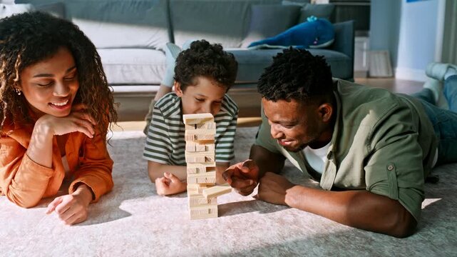 Parents son lying floor building wooden block tower. Home board game weekend.