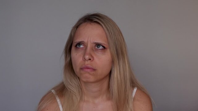 Young blonde woman stares into the distance and nervously looks around with a lost, confused expression, portraying disorientation, emotional numbness and a sense of detachment from reality