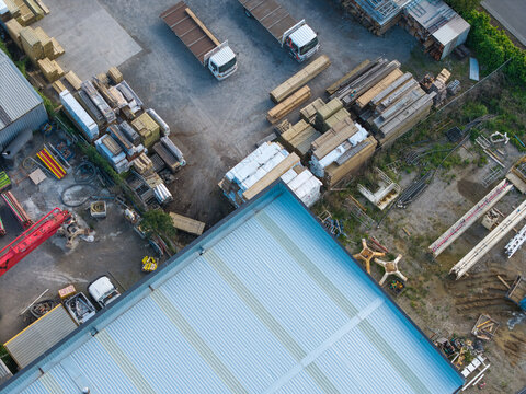 Melbourne, VIC, Australia - 06 October 2026: Aerial view of industrial area in Knox and Bayswater featuring factory buildings, stacks of timber, flatbed trucks, and open fields.
