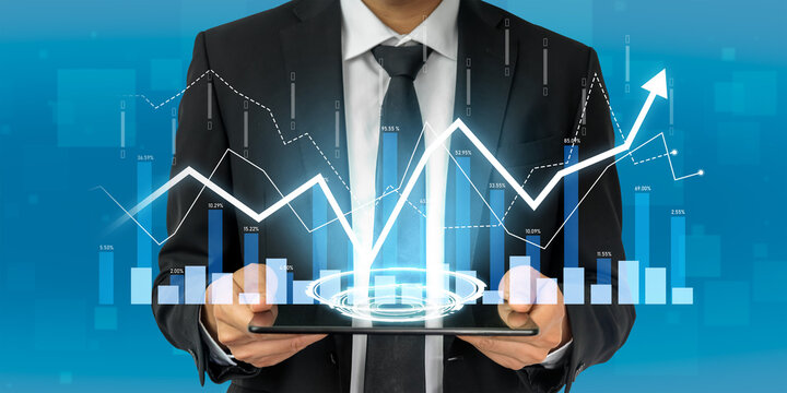 A businessman in formal attire holds a tablet displaying dynamic financial data visualizations, showcasing growth trends and market analysis in a modern office setting. Scalp